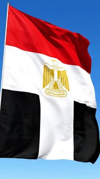 The national flag of Egypt waves against a clear blue sky