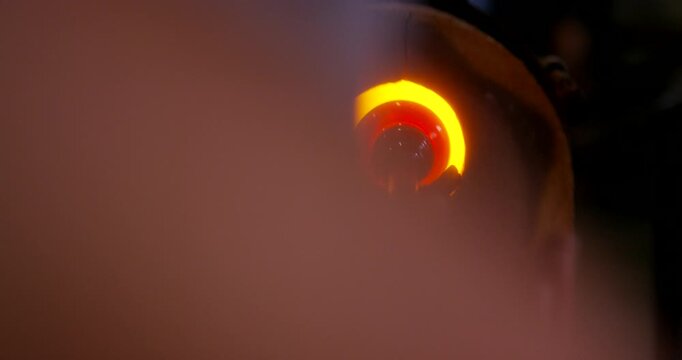 A artisan glass blower working with colored glass pigments and molten glass in a studio