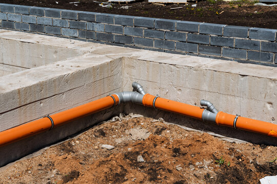 Drainage Pipe Details. Soil Bedding And Trench Installation Of Drainage Pipes In Foundation. Installation Details Of Orange Drainage Pipelines Within Concrete Foundation Corners And Trenches