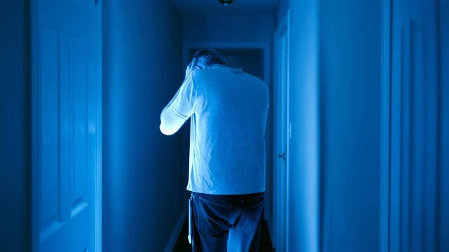 Man suffering from mental breakdown and emotional pain in dark hallway. Frustrated caucasian man holding head in distress. Concept of depression and psychological trauma.