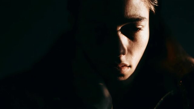 Young man in deep emotional struggle and mental stress. Portrait of sad boy experiencing burnout and inner turmoil. Dramatic psychological concept of dissociation.
