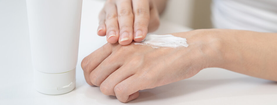 Health skin care, beauty smile asian young woman, girl  hand applying, putting moisturizer on her arm, shoulder after shower bath at home. Skin body cream moisturizing lotion, routine in the morning.