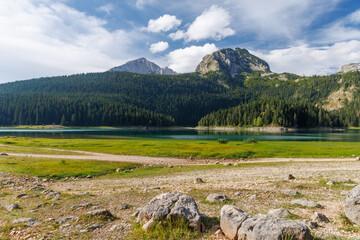 Fototapeta premium Calm lake with forest reflection under blue sky