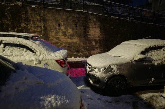 Street view of snowed-in vehicles in Manali. The cars are heavily blanketed by fresh winter snow, showing the aftermath of a heavy Himalayan blizzard.