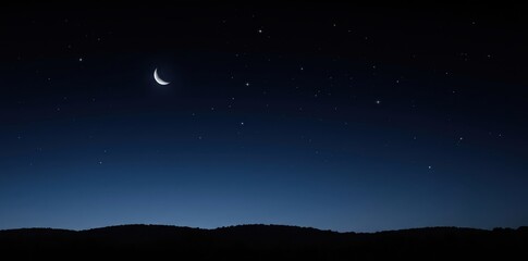 Fototapeta premium A clear dark night sky filled with numerous bright stars and a slender crescent moon hanging above a dark silhouetted rolling landscape of hills
