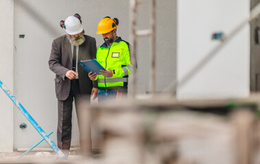 Fototapeta premium Engineer and businessman inspecting house construction site while discussing building project