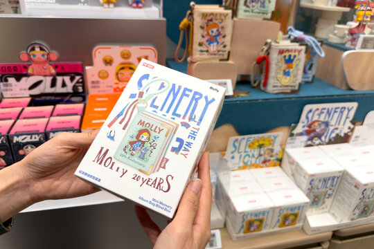 PENANG, MALAYSIA - JUL 03, 2026: Hand holding Pop Mart Molly 20 Years mini memory album bag blind box inside retail toy store.