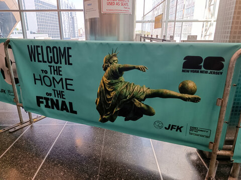 A promotional banner promoting the 2026 FIFA World Cup featuring the Articles of Liberty in a dynamic pose as a football player kicks a ball at John F. Kennedy Airport, New York, USA, June 19, 2026