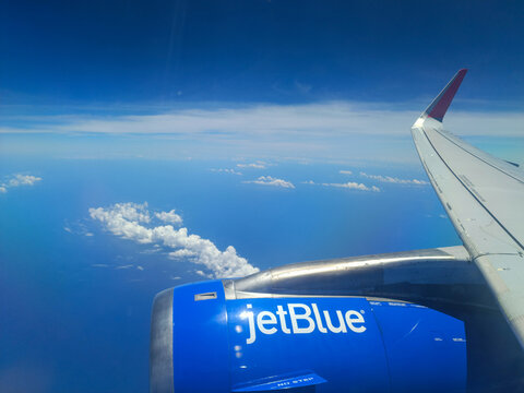 A view from the window of a JetBlue airplane shows the engine, wing and clouds over the ocean as it approaches New York City, USA, June 19, 2026