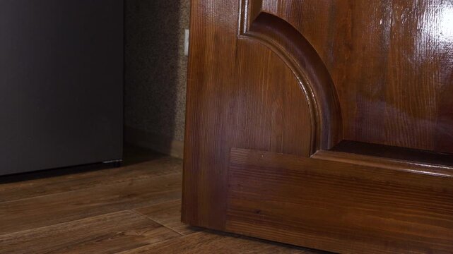 Man in jeans and sneakers opening wooden door, Man steps inside apartment and closes wooden door