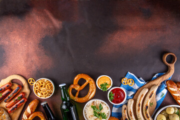 Fototapeta premium Oktoberfest picnic and barbecue food, bavarian party menu, bavarian sausages, pretzels, potato, sauerkraut, beer bottles, with picnic basket, checkered napkin tablecloth, Oktoberfest festive ribbon