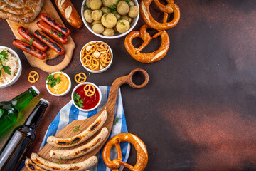 Fototapeta premium Oktoberfest picnic and barbecue food, bavarian party menu, bavarian sausages, pretzels, potato, sauerkraut, beer bottles, with picnic basket, checkered napkin tablecloth, Oktoberfest festive ribbon
