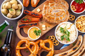 Fototapeta premium Oktoberfest picnic and barbecue food, bavarian party menu, bavarian sausages, pretzels, potato, sauerkraut, beer bottles, with picnic basket, checkered napkin tablecloth, Oktoberfest festive ribbon