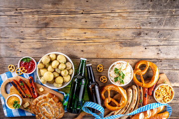 Fototapeta premium Oktoberfest picnic and barbecue food, bavarian party menu, bavarian sausages, pretzels, potato, sauerkraut, beer bottles, with picnic basket, checkered napkin tablecloth, Oktoberfest festive ribbon
