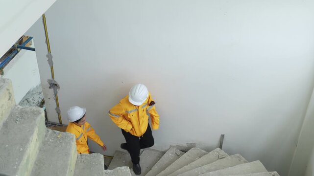 Construction workers inspecting an unfinished building while climbing stairs, promoting safety, teamwork and construction site management.