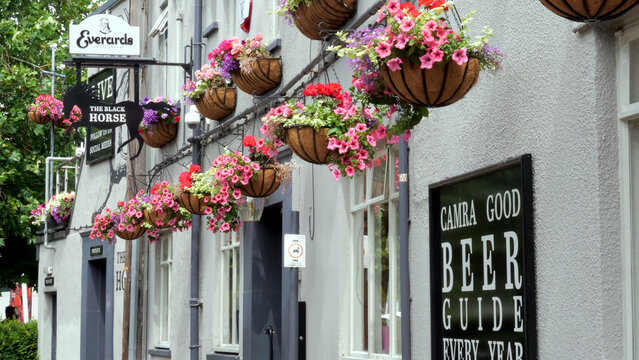 Leicester, England, UK - 6 July 2026: Traditional English pub exterior, British tavern facade with blooming flower baskets, classic bar storefront, rustic street view, hanging petunias, travel to UK