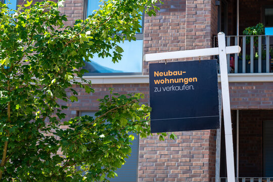 Closeup view of a sign in front of a modern building advertising apartments for sale in German