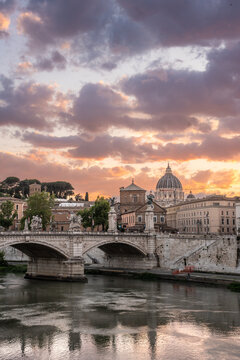 Beautiful illuminated view of Rome, Italy with Saint Peters Basiica, historic architecture, bridges and Tiber River under evening sky. 