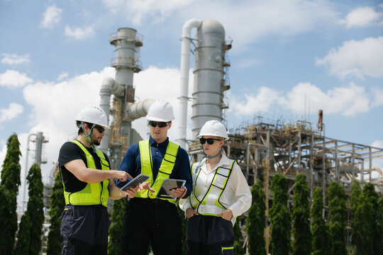 Engineers collaborating on construction site with industrial background in hard hats and safety vests