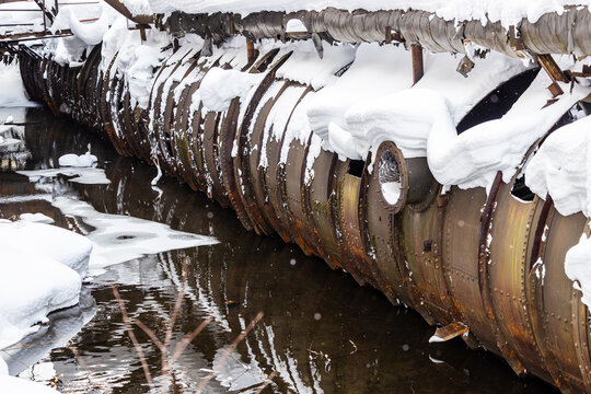 old snowy pipeline in puddle of melted snow