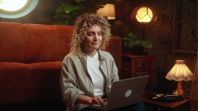 Horizontal video of relaxed curly haired woman finishing remote work and closing laptop after productive day at home. High quality 4k footage