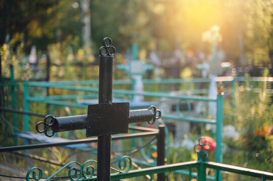 Silhouette of a black metal cross on a grave during a beautiful dramatic sunset, spiritual memory concept