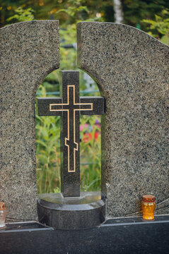 serene grave marker with cross in cemetery side view with lanterns and granite material, black and gold colors, still life scene, editorial use case, memorial setting.