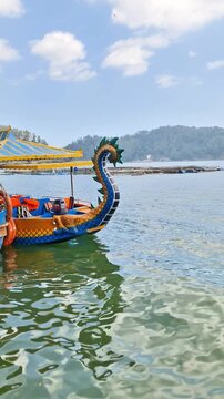 Ponorogo, Indonesia - 8 July, 2026: Editorial scenic shot of colorful recreational speedboats with racing decals moored at a mountain lake during a sunny weekend.