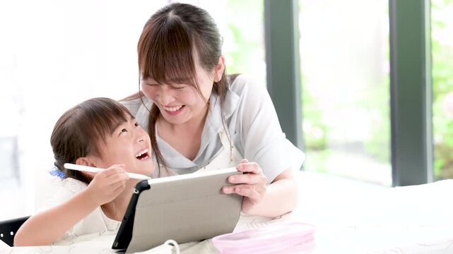 [スローモーション]勉強がわかった！と見つめ合う喜ぶ、タブレットを使って一緒に学習する母親と小学生の女の子・家庭で学ぶ親子のライフスタイルの動画