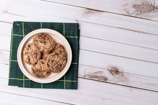 Chocolate chip cookies on a plate over wooden table with copy space
