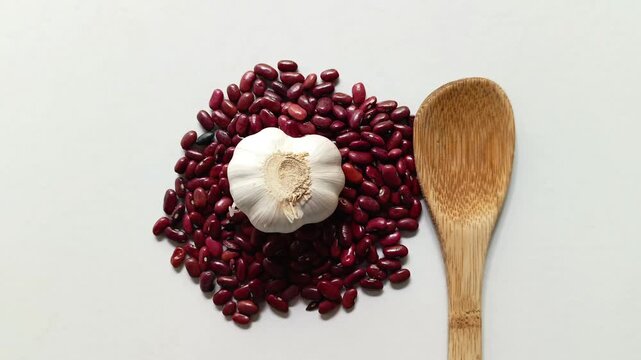 Raw red beans Phaseolus vulgaris with fresh garlic Allium sativum and wooden spoon from Guatemala