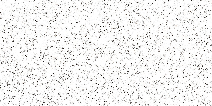 A high-angle shot of scattered black dots on a white background, creating a textured, abstract pattern.
