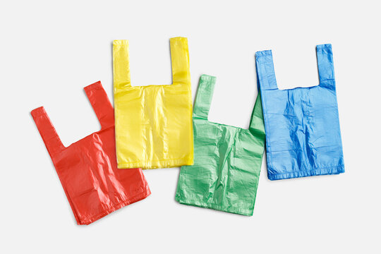 Colored single-use plastic shopping bags on light gray background, copyspace. Top view red, yellow, green, blue grocery bag, everyday consumer packaging and use of disposable plastic products.