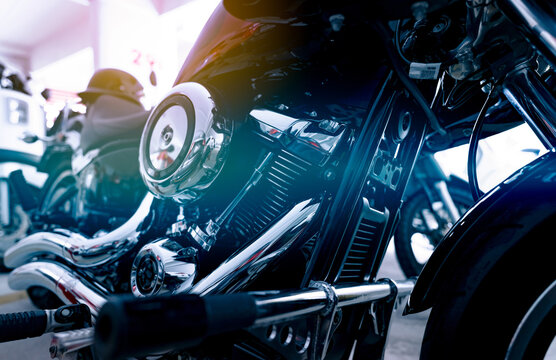 Selective focus on a motorcycle engine. Closeup motorcycle exhaust pipe, engine guard, air filter, and rear brake pedal. Motorcycle industry. Shiny chrome motorbike engine. Vintage motorbike.