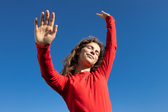 dynamic shot of a young woman dancing dreamily in the sunlight under a cloudless blue sky. Energy, freedom, joy, and a call to action. copy space. A love for life, dreams, and positive mindset.