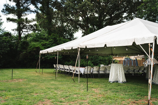 Large white event tent with tables and chairs set in a backyard