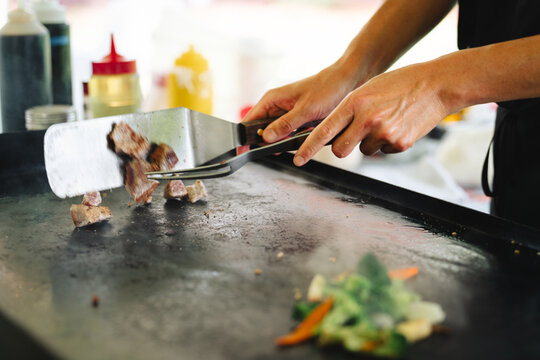 Chef cooking meat on flattop griddle at outdoor market