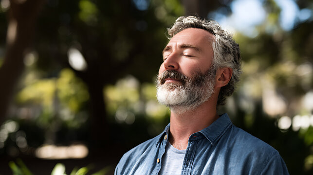 serene portrait of man practicing mindfulness breathing outdoors with sunlight and trees behind