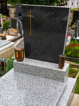 New grave with an unmarked headstone and granite grave cover, lantern, and vase in a village cemetery in Austria