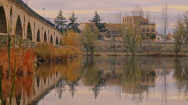 Masonry Pointed arch Stone bridge (Puente de Piedra) across the river Duero in Zamora, Castile-Leon, Spain. Reflection in the water.