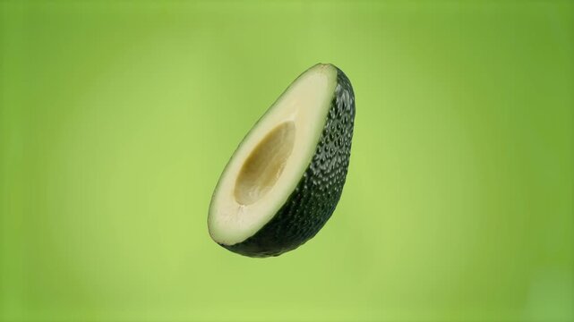 A close-up 3D rendering of a perfectly cut avocado half without the pit, displaying its rich green texture and dark bumpy skin. Suspended against a chroma key green screen background, this food asset 
