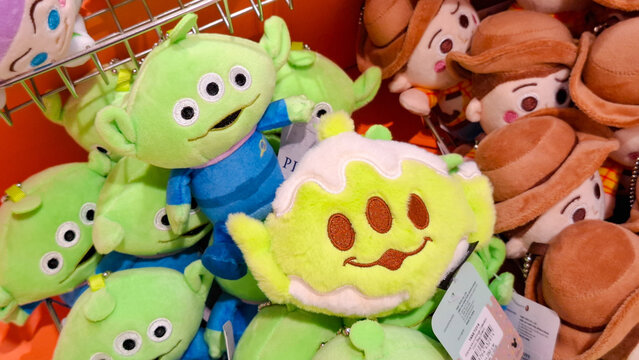Assorted pile of collectible Disney Pixar Toy Story character plush dolls showcasing three eyed alien variations and woody keychains on July 3, 2026 in Bangkok, Thailand