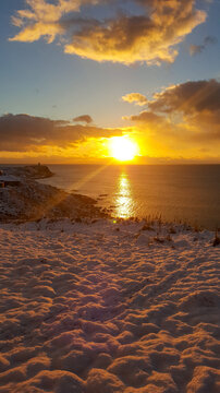 A stunning sunrise casts golden light over a snowy coastline in the Kuril Islands.