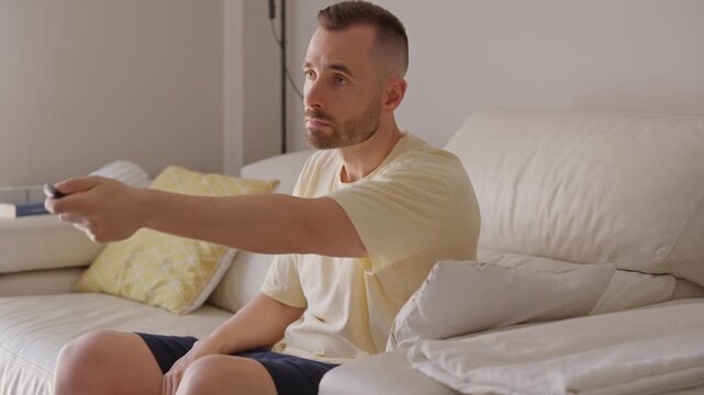 Casual young man sitting on sofa watching television