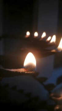 Lighting a traditional oil lamp (Diya) during Diwali festival of lights or Buddhist ritual worship.