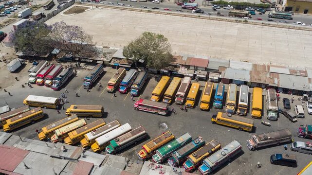 Aerial view of a busy bus terminal with numerous yellow school buses parked in an open lot in guatemala.