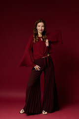 Fototapeta premium Stylish mature woman exuding elegance in a stunning maroon ensemble on a vibrant backdrop