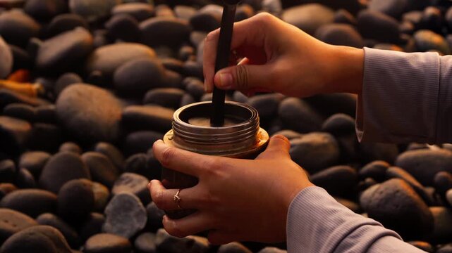Hand Pouring Freshly Ground Coffee into a Moka Pot at Sunset on the Beach