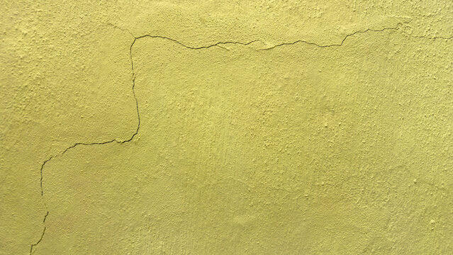 Background featuring the texture of a yellow-painted concrete wall cracked after an earthquake