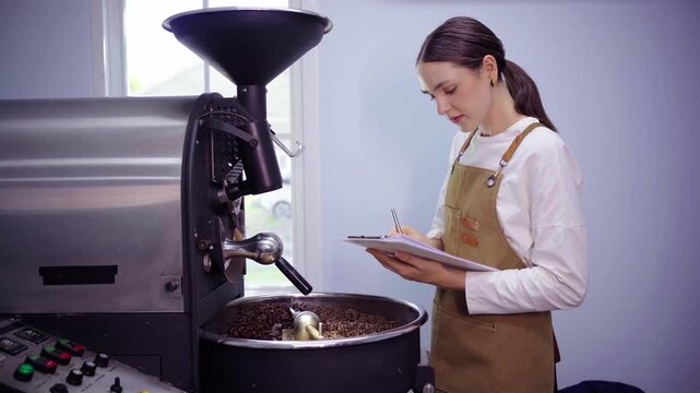 Female roaster taking notes on clipboard at roasting machine